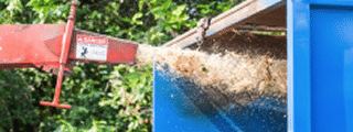 Brush chipper shooting chips into a dumpster